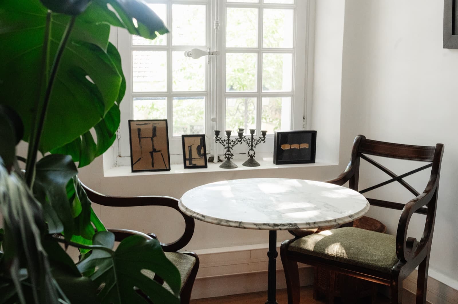 Table en marbre, chaises anciennes et œuvres posées en fenêtre