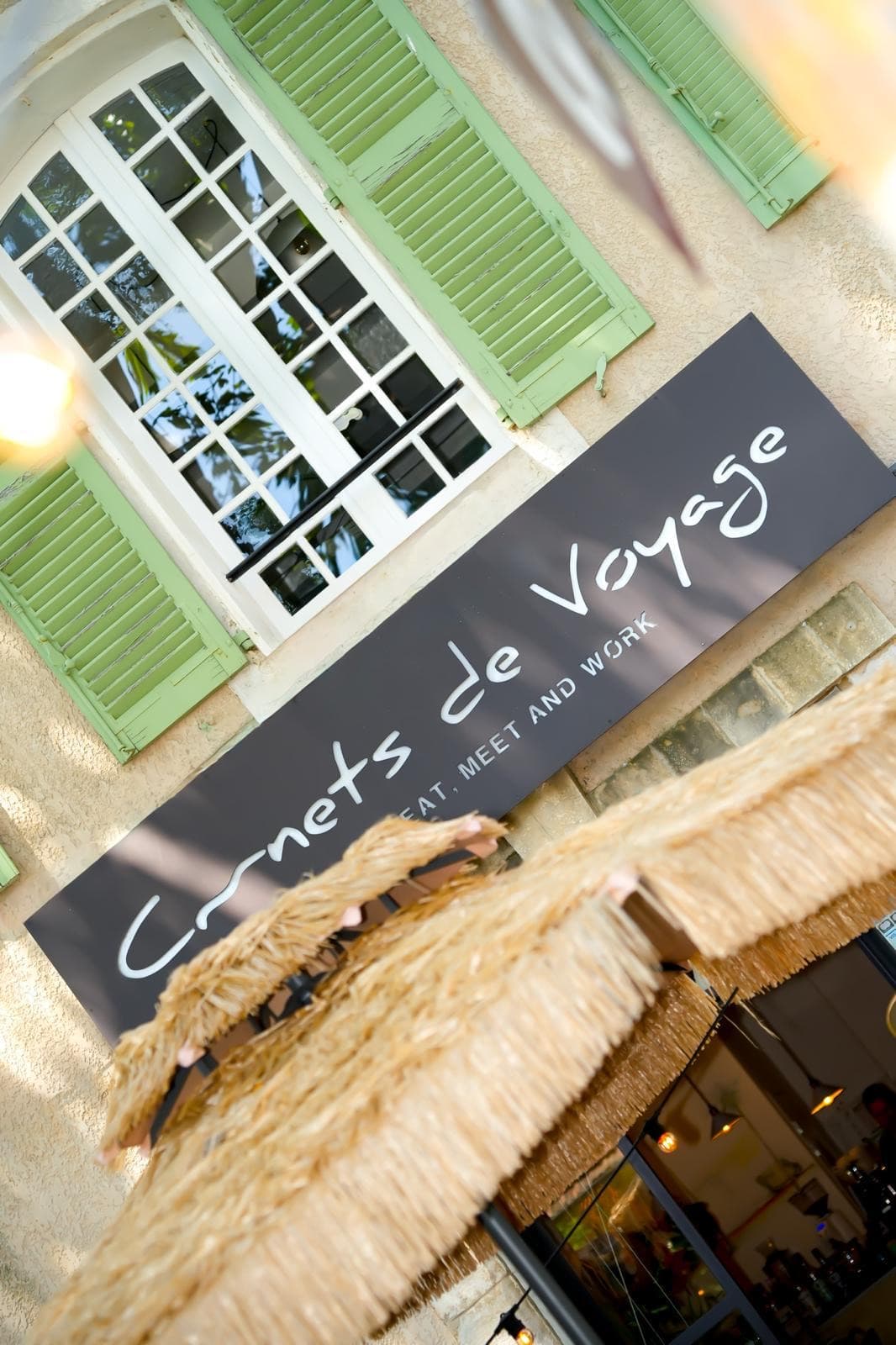 L'enseigne Carnets de Voyage sur la façade de la maison, volets verts
